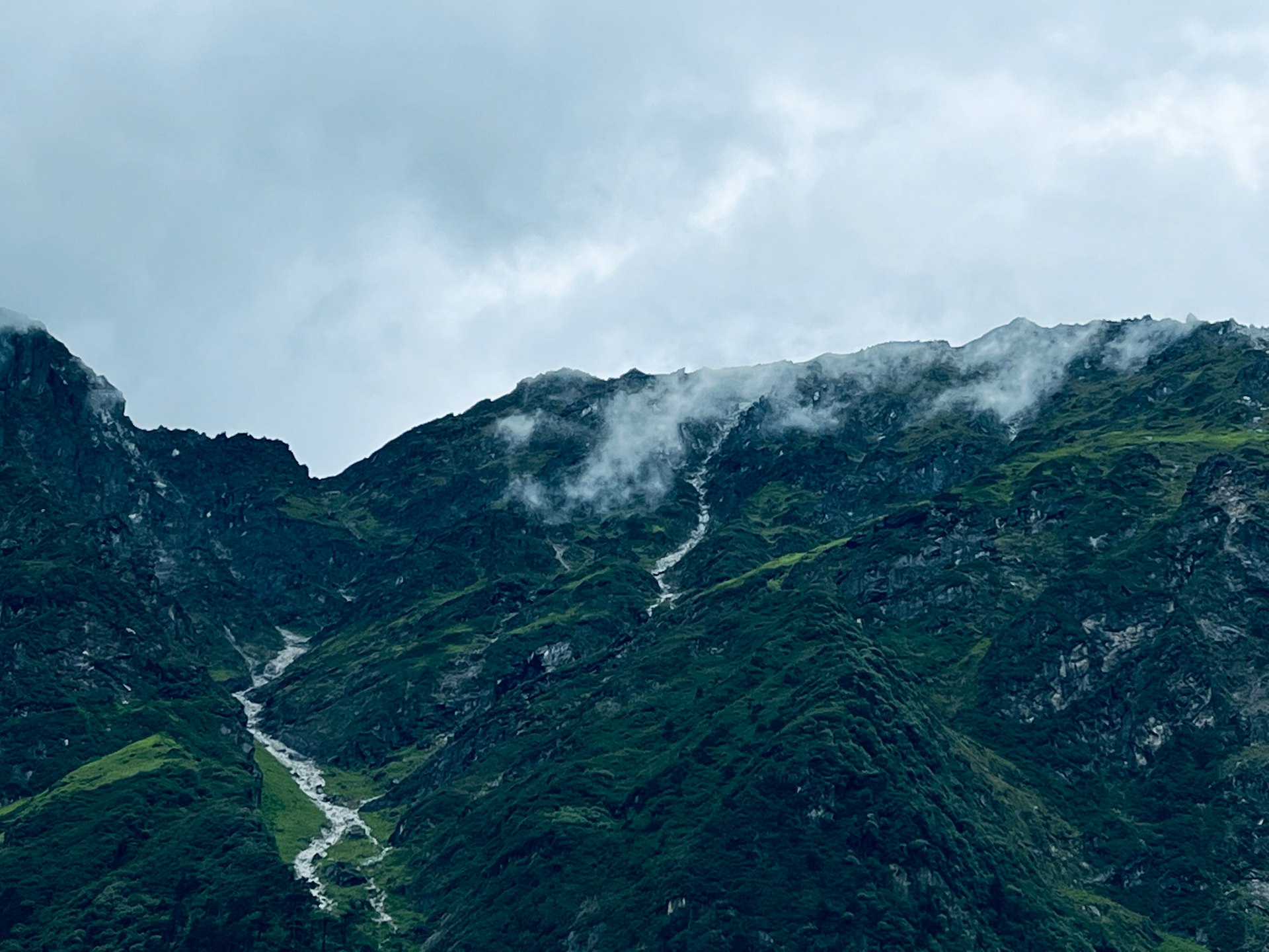 a very tall mountain with some clouds in the sky
